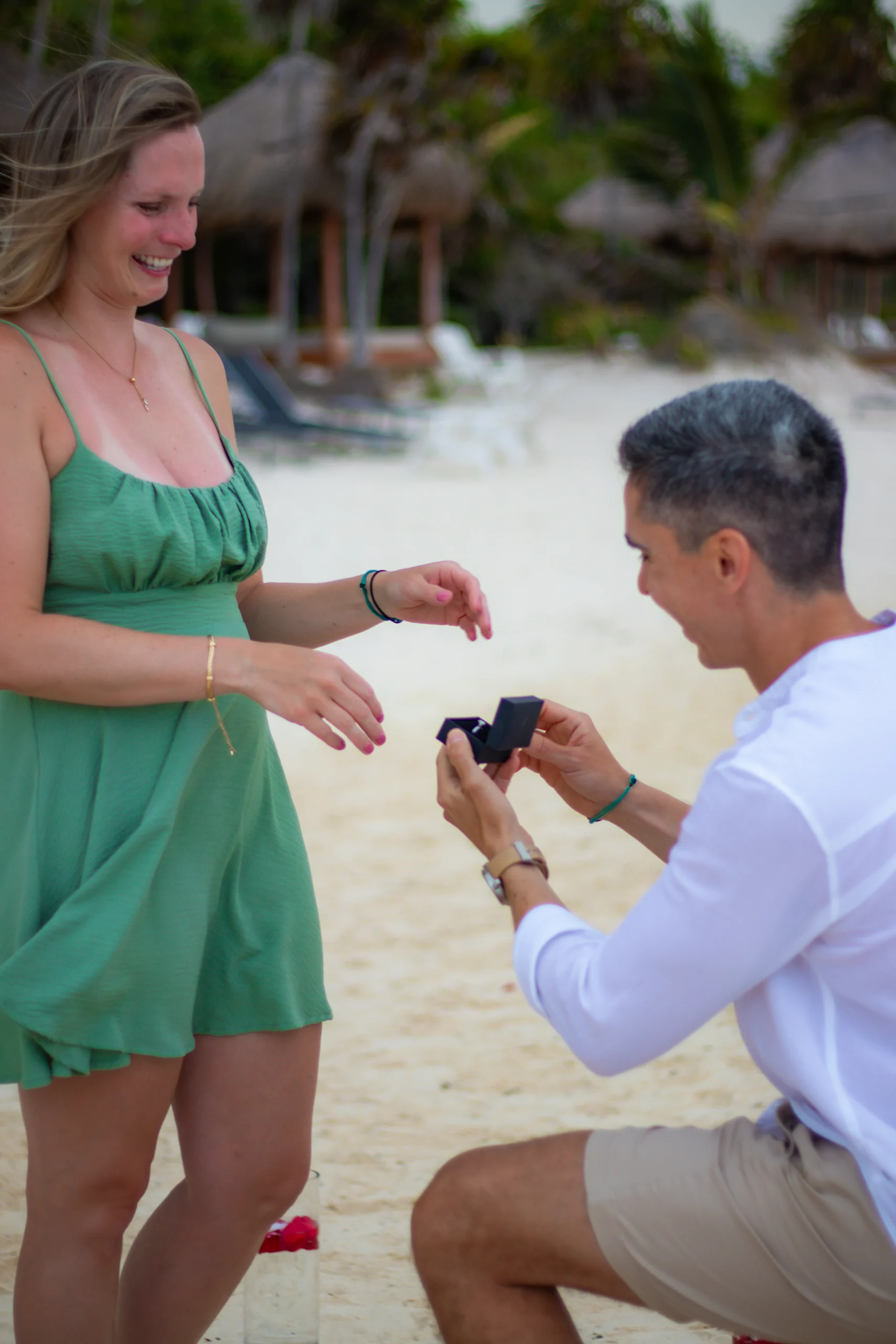 Primer plano de un hombre entregando un anillo de compromiso a su pareja durante un momento de propuesta en la playa.