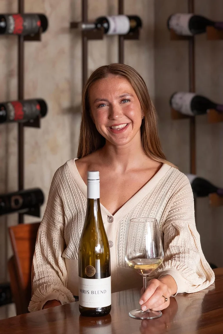 Mujer sonriente en cava de vinos con botella de vino blanco - sesión de personal branding