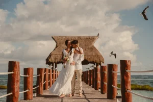 Wedding photographer in Riviera Maya – bride and groom kissing on a pier with palapa in Playa del Carmen, Joice Dahianna