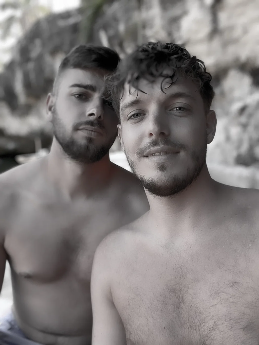 Sepia-toned portrait of a shirtless gay couple standing close together, captured by an LGBTQ photographer in Playa del Carmen
