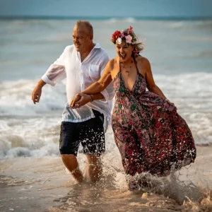 Couple running and laughing in the ocean during a couple photography session in Playa del Carmen